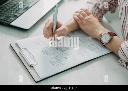 Close-up of businesswoman hand making notes in calendar diary on desk. Female hand planning on calendar Stock Photo