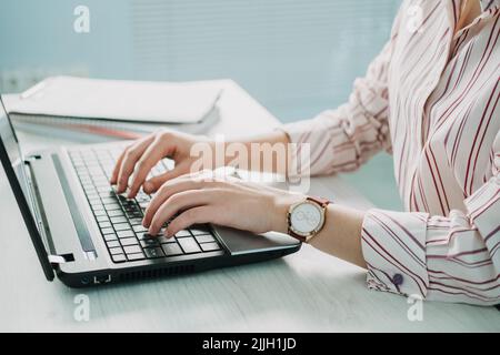 Close-up of businesswoman hand making notes in calendar on laptop. Female hand typing Stock Photo