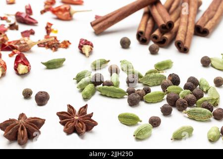 Allspice among cardamom seeds, star anise and cinnamon sticks. Close up. Top view. White background Stock Photo