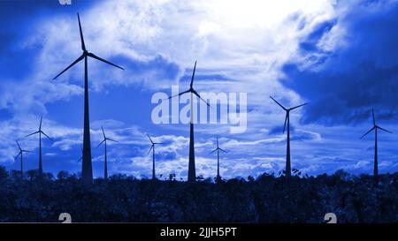 Electrical windmills silhouetted in a dark blue sky Stock Photo