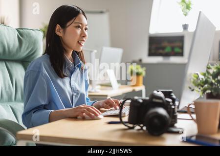 Asian Female Photographer Working On Computer Editing Photos Indoor Stock Photo