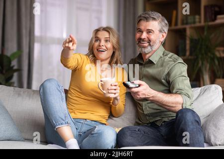 Portrait Of Happy Middle Aged Spouses Watching Comedy Movie On Tv Together Stock Photo