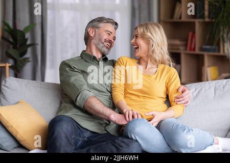 Married Middle Aged Couple Having Fun While Relaxing On Couch At Home Stock Photo