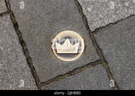 Bratislava, Slovakia - 19 April 2012: Crown-shaped tile on the ground as symbol of Coronation Trail. Brass crown marker in the cobblestone street Stock Photo