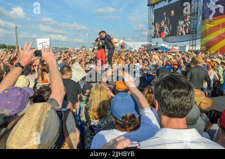 Bruce Springsteen performs with young male fan amidst the crowd at the New Orleans Jazz and Heritage Festival on April 29, 2012 Stock Photo