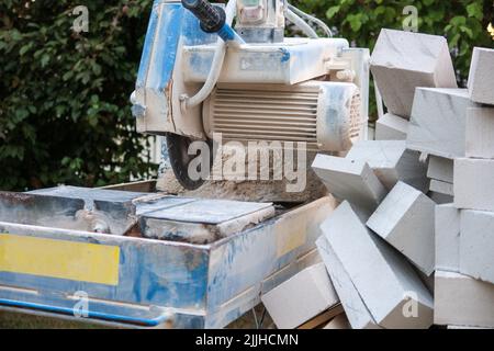 Next to a circular saw for stones there is a wheelbarrow with stone scraps Stock Photo