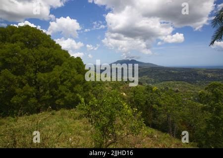 Blue sky with clouds over the mountains, green summer forest in Caribbean island Stock Photo
