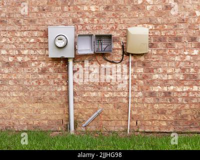 Residential home utility boxes for electric meter, phone and cable TV on the side of the house. Stock Photo