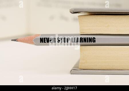 Education concept. In the book between the pages lies a pencil with the inscription - Never stop learning Stock Photo