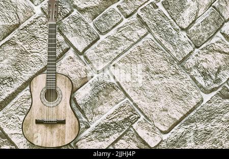 Gray silver acoustic guitar on gray brick wall Stock Photo