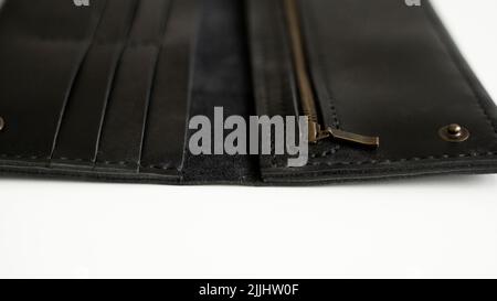 Details of man's handmade wallet on a white surface. Wallet made of genuine black leather with a slots for cards and big zip pocket on a white Stock Photo