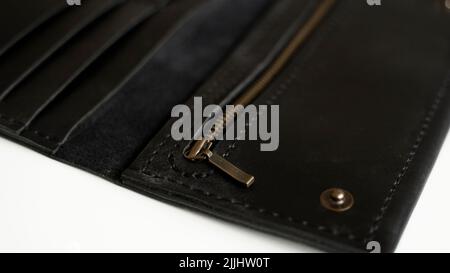 Details of man's handmade wallet on a white surface. Wallet made of genuine black leather with a slots for cards and big zip pocket on a white Stock Photo