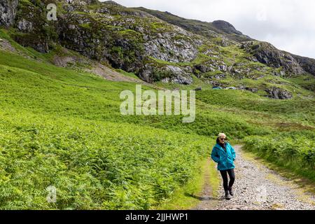 Glen Coe in the highlands of Scotland, blonde female hiker model released wearing hiking gear walks along the Glencoe valley trail path,Scotland,UK Stock Photo