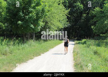 Young woman wearing headphones walking on the Des Plaines River Trail at Iroquois Woods in Park Ridge, Illinois Stock Photo