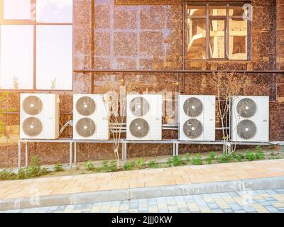 A row of double industrial air conditioners is mounted on a brown marble tiled wall. View outside. Stock Photo