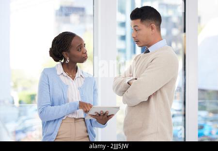 Could you send me those documents. two business colleagues using a digital tablet while having a discussion. Stock Photo
