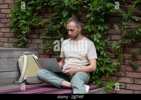 Concentrated young man freelance web developer working remotely at outdoor work environment Stock Photo
