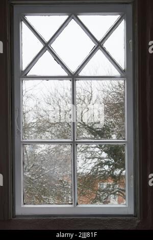 Closeup of a glass window from inside, looking out on cold weather in the morning. A wooden windowpane with bad insulation, shut and closed with a Stock Photo