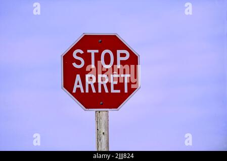 A horizontal image of a red bilingual stop sign located in rural New Brunswick Canada Stock Photo
