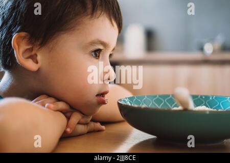 Little boy doesn't want to eat his bowl with porridge. Healthy food. Healthy breakfast. Healthy meal. Stock Photo