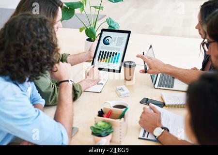 Business people using digital tablet computer discussing financial graph data on mobile touchscreen device in meeting Stock Photo