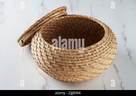 A handicraft in the form of a storage container with a lid made of woven rattan Stock Photo