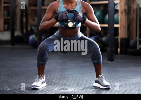 Never give up, great things take time. a woman working out with a kettle bell at the gym. Stock Photo