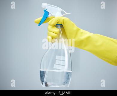Keep your home safe and clean. a hand holding a spray bottle and wearing yellow gloves. Stock Photo