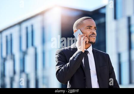 Lets make some calls. a young businessman using a phone in the city. Stock Photo