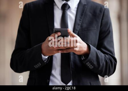 Take work wherever you go. an unrecognizable businessman using a phone in the city. Stock Photo