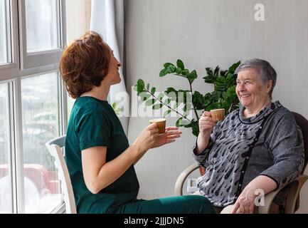 Mother and daughter spend time together on country house veranda, drinks coffee. concept of warm trusting relationships, selective focus Stock Photo