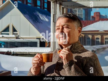Smiling mature female in warm clothes having cup of hot tea coffee on terrace. Day of Older Persons. Selective Focus. lifestyle concept happy. Stock Photo