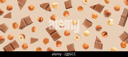 Falling pieces of milk chocolate and hazelnuts on beige background Stock Photo