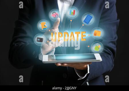 Businesswoman with tablet computer on dark background. Concept of update Stock Photo