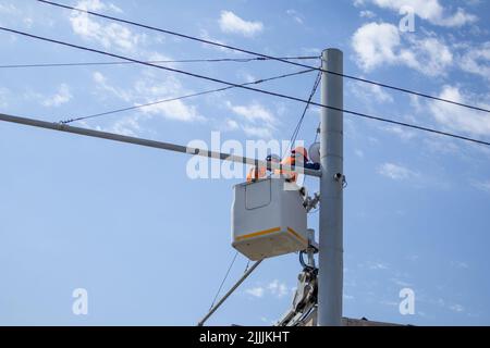 two male electrician workers. electricians in the crane cradle are working Stock Photo