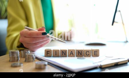 Woman pointing on word finance collected of wooden blocks in row Stock Photo