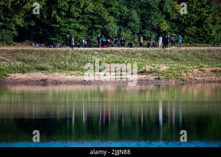 Porta Westfalica, Germany. 27th July, 2022. Relatives of the two missing bathers, who failed to surface for unexplained reasons on Sunday (24.07.2022), stand on the shore of a quarry pond. According to a spokesman for the fire department, some parts of the lake are 30 meters deep. Experts from the police will now search for the two people with an underwater probe. Credit: Lino Mirgeler/dpa/Lino Mirgeler/dpa/Alamy Live News Stock Photo