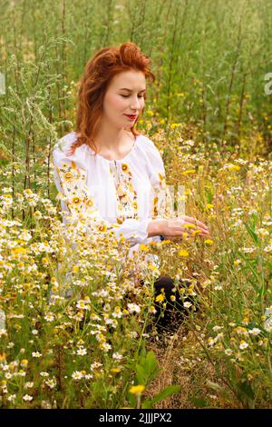 A woman in a Ukrainian embroidered shirt in a field with a bouquet of wild flowers Stock Photo