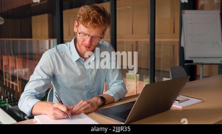 Portrait of successful confident young businessman make notes in office. Stock Photo