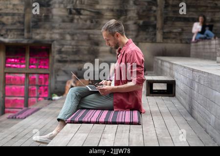 Focused concentrated student guy using laptop studying outdoors, freelancer working outside Stock Photo