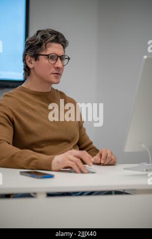 A man sitting at the computer and looking concentrated Stock Photo