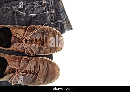 Stylishly shabby vintage brown leather shoes and black jeans on a white background Stock Photo
