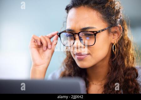 Making sure she doesnt miss a detail. an attractive young businesswoman working on her laptop in the office. Stock Photo