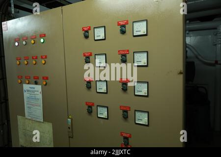 ship engine room dashboard with plenty of bottoms, indicators, small indication lamps and schematics of engines and generators, voltmeters, amperemete Stock Photo