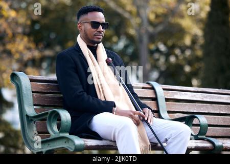 Life is not about finding yourself. a young man sitting on a bench in a park. Stock Photo