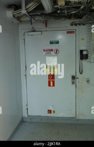 Cruise ship engine room interior with water tight doors electrical and diesel engines, water pipes, measuring instruments, warning signs Stock Photo