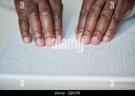 Close-up of senior blind man reading book with braille language at table Stock Photo