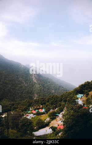 A vertical shot of greenery huge mountains behind houses Stock Photo