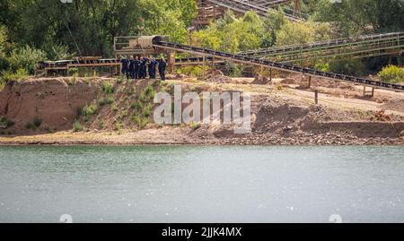 Porta Westfalica, Germany. 27th July, 2022. Police officers stand on the edge of the gravel pond where two people failed to surface for unexplained reasons while swimming on Sunday (24.07.2022). According to a spokesman for the fire department, some parts of the lake are about 30 meters deep. Experts from the police now want to search for the two people with an underwater probe. Credit: Lino Mirgeler/dpa/Alamy Live News Stock Photo