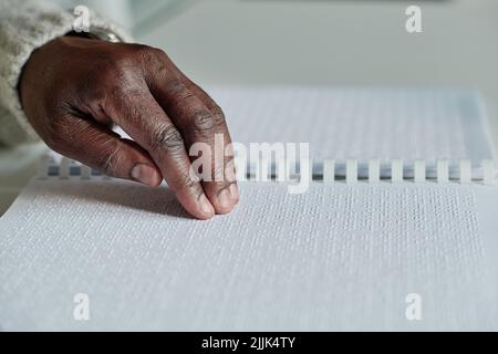 Close-up of senior blind man reading braille in opened book at table Stock Photo